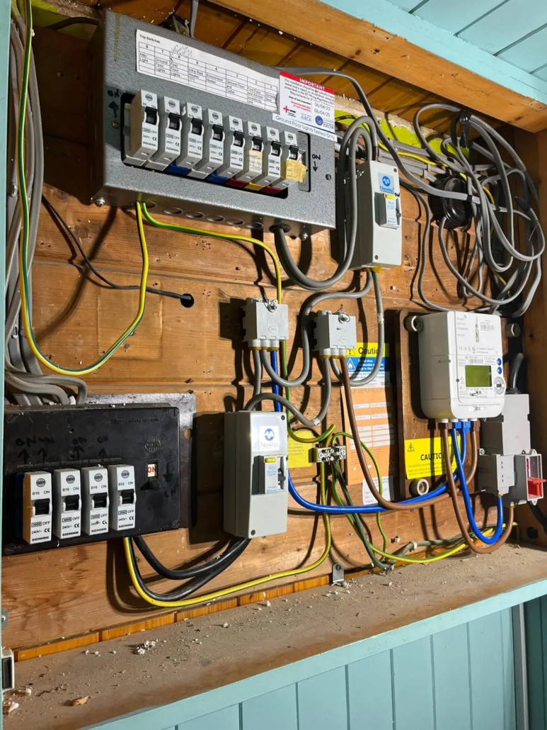 A consumer unit, meter and isolators on a timber backboard