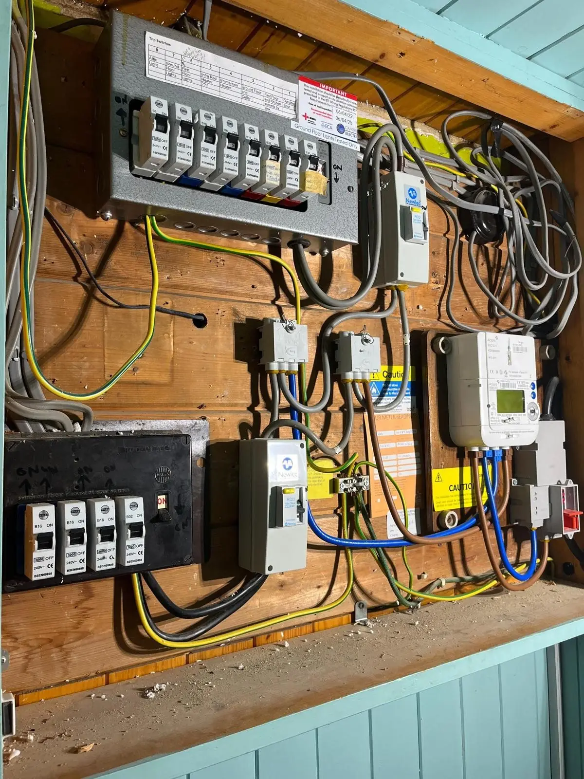 A consumer unit, meter and isolators on a timber backboard